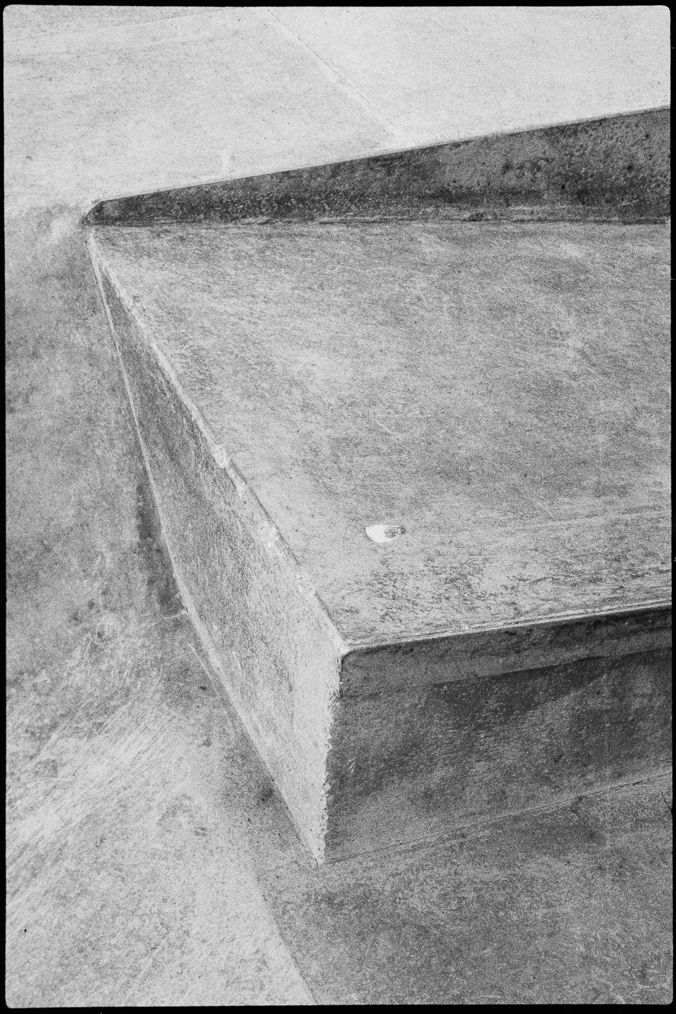 Worn concrete ledge in a skatepark, black-and-white film, July 2024