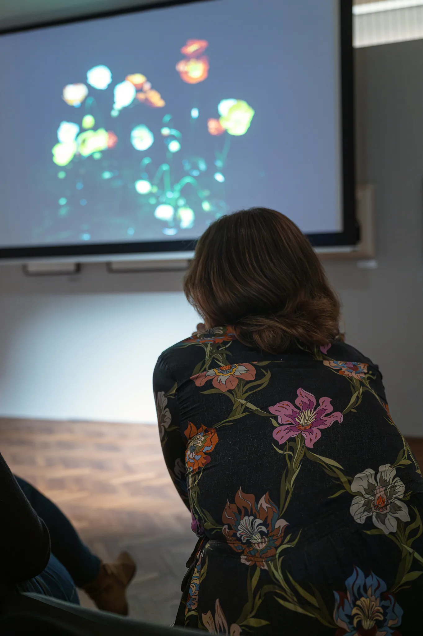 A visitor in a floral dress watching Cig Harvey's flower pictures on screen, Leica Gallery Vienna, September 2026